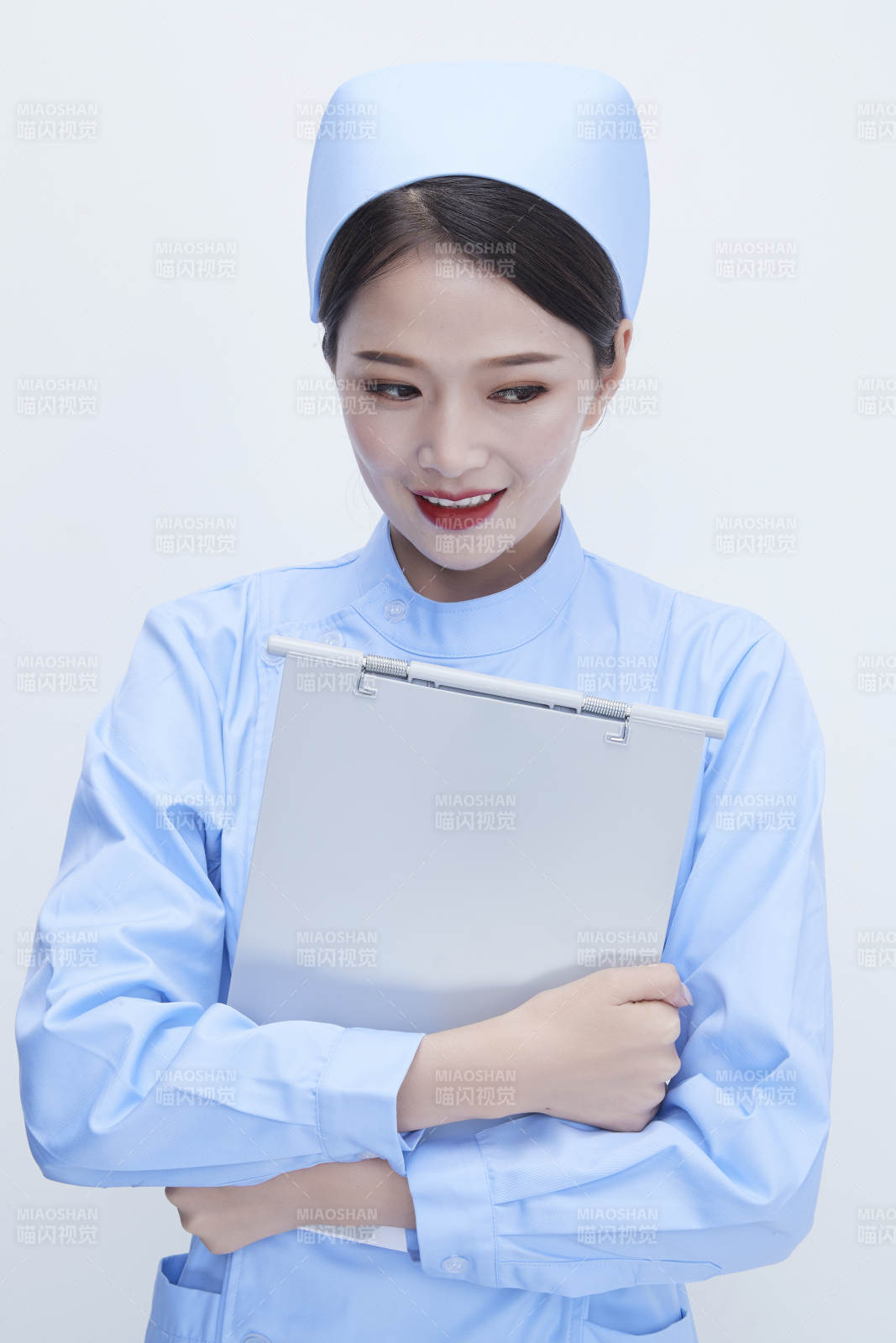白背景里穿蓝色护士服手持病历夹的美女护士图片