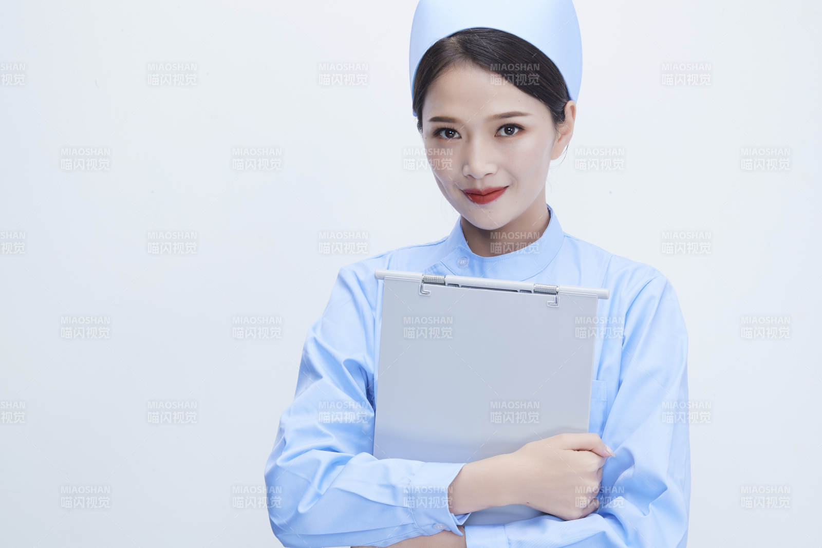 白背景里穿蓝色护士服手持病历夹的美女护士图片