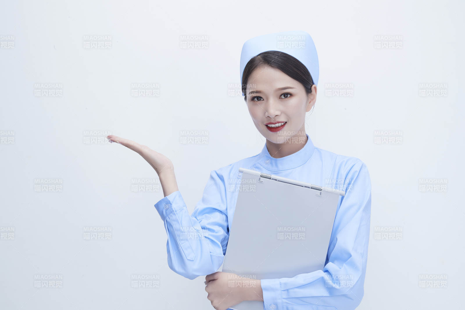 白背景里穿蓝色护士服手持病历夹的美女护士图片