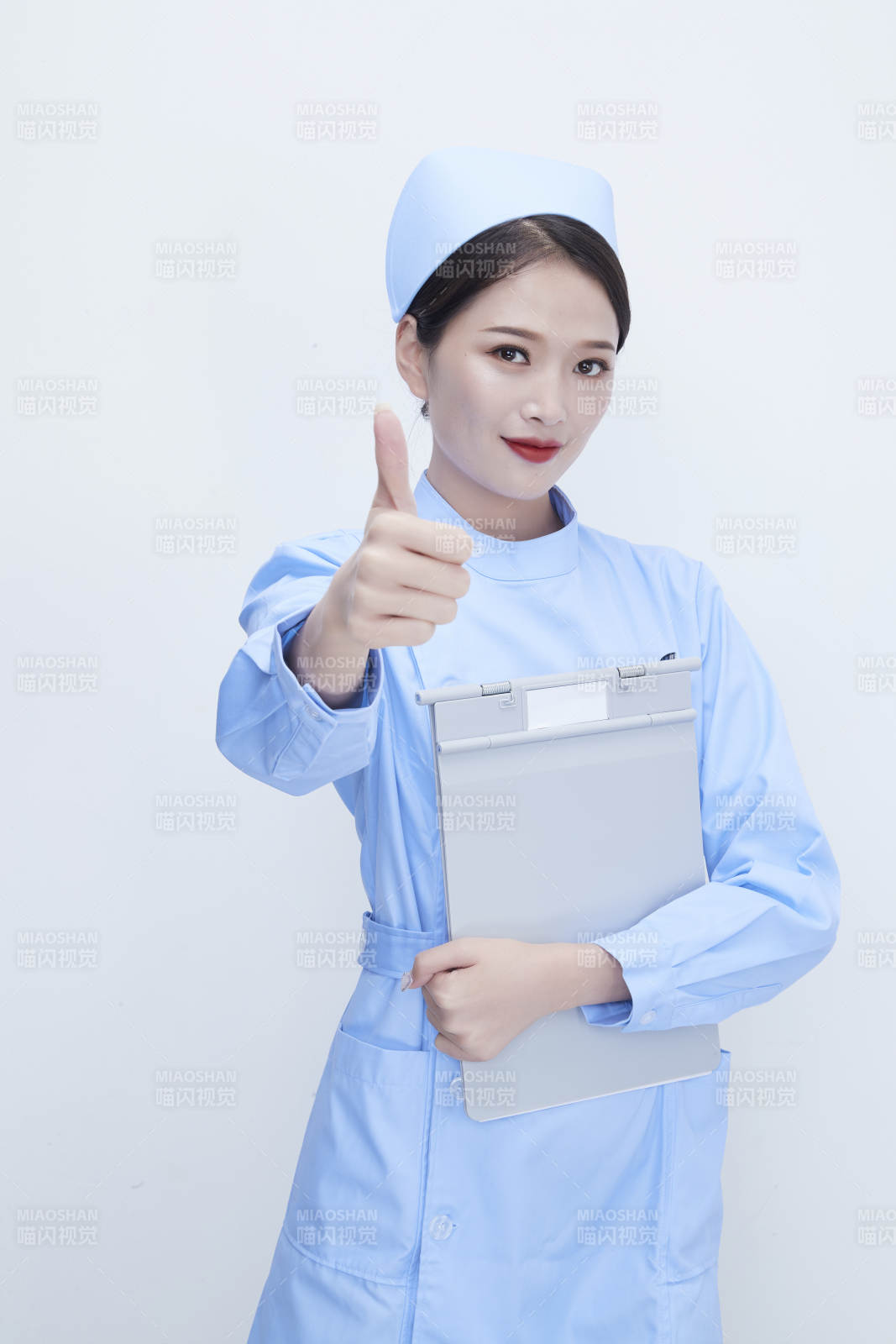 白背景里穿蓝色护士服手持病历夹的美女护士图片