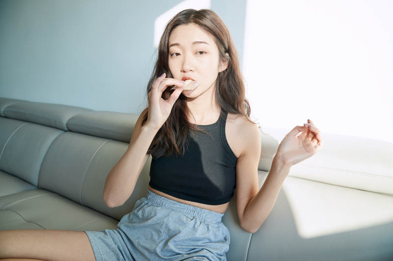 在家在沙发上享受美食的亚洲少女图片