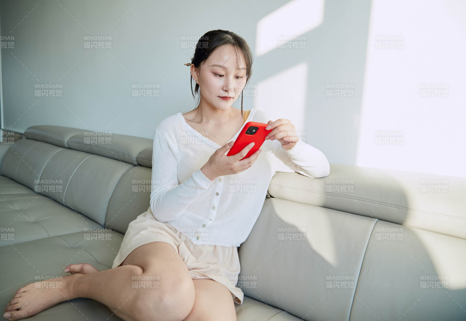 在沙发床上玩手机的年轻亚洲女性图片