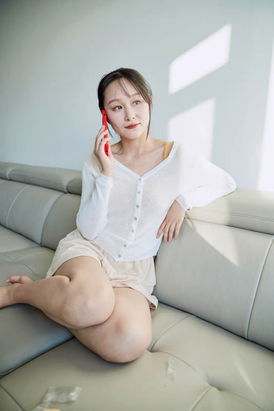 在沙发床上玩手机的年轻亚洲女性图片