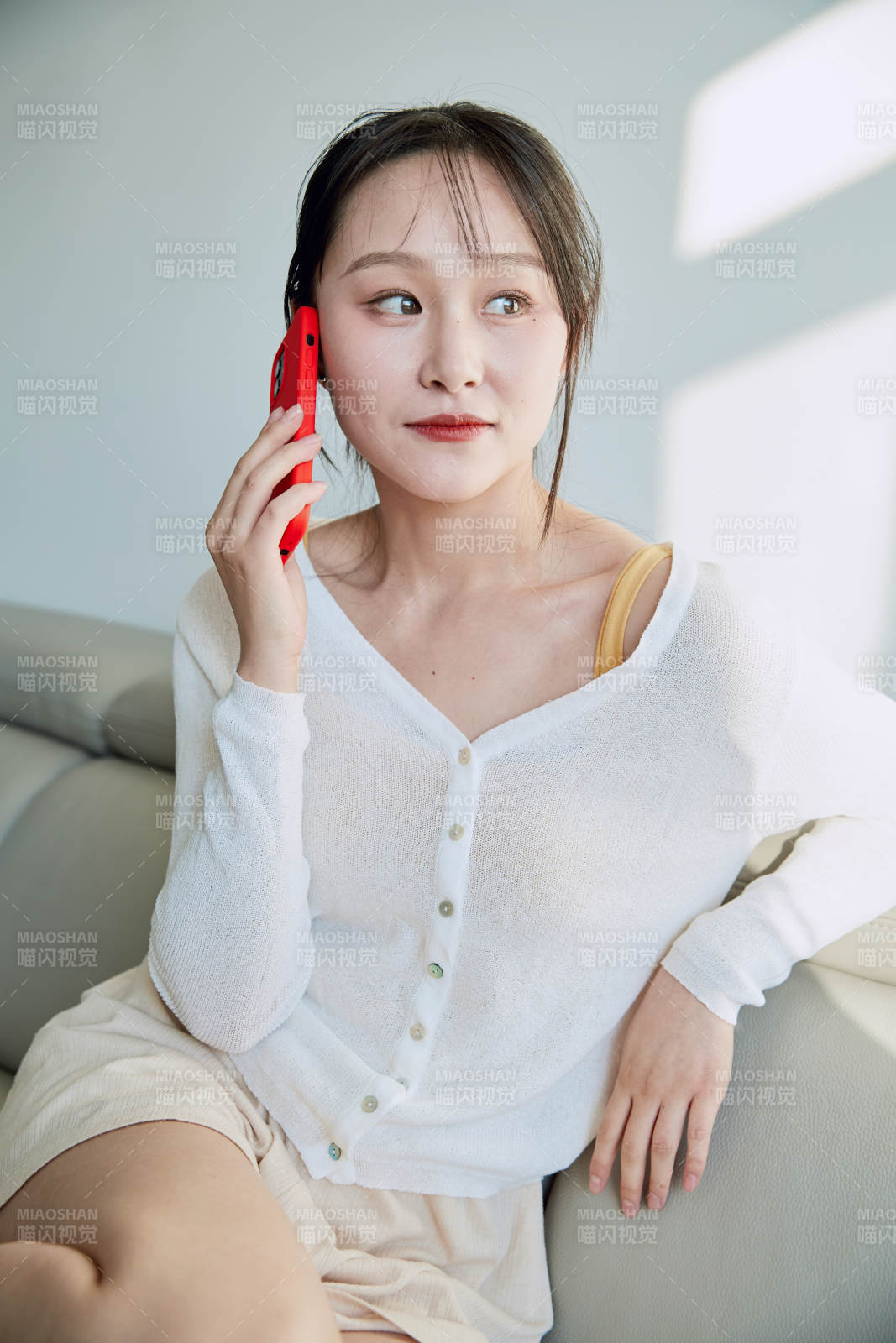 在沙发床上玩手机的年轻亚洲女性图片