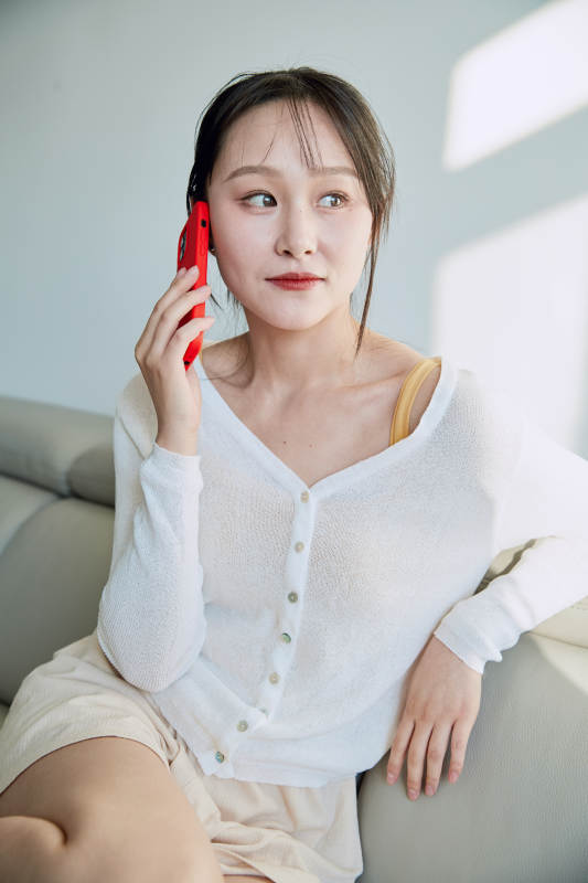 在沙发床上玩手机的年轻亚洲女性图片