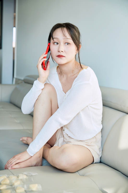 在沙发床上玩手机的年轻亚洲女性图片