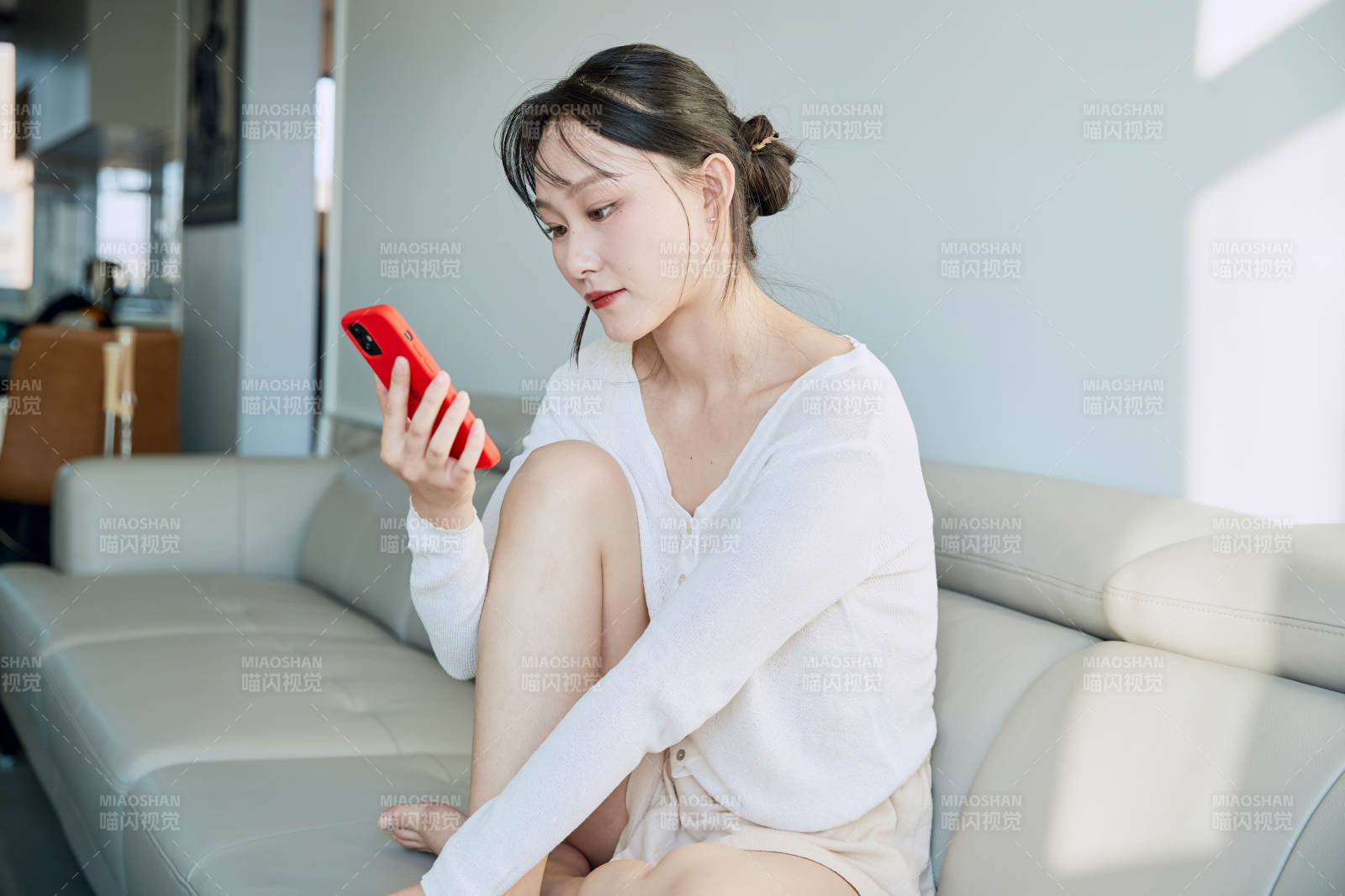 在沙发床上玩手机的年轻亚洲女性图片