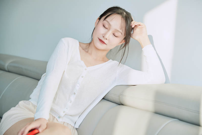 在沙发床上玩手机的年轻亚洲女性图片