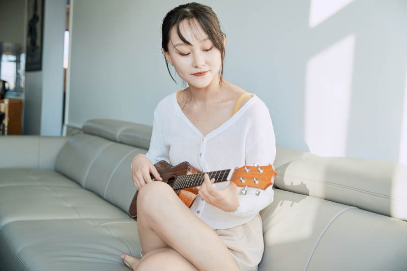 坐在沙发上弹奏尤克里里的少女图片