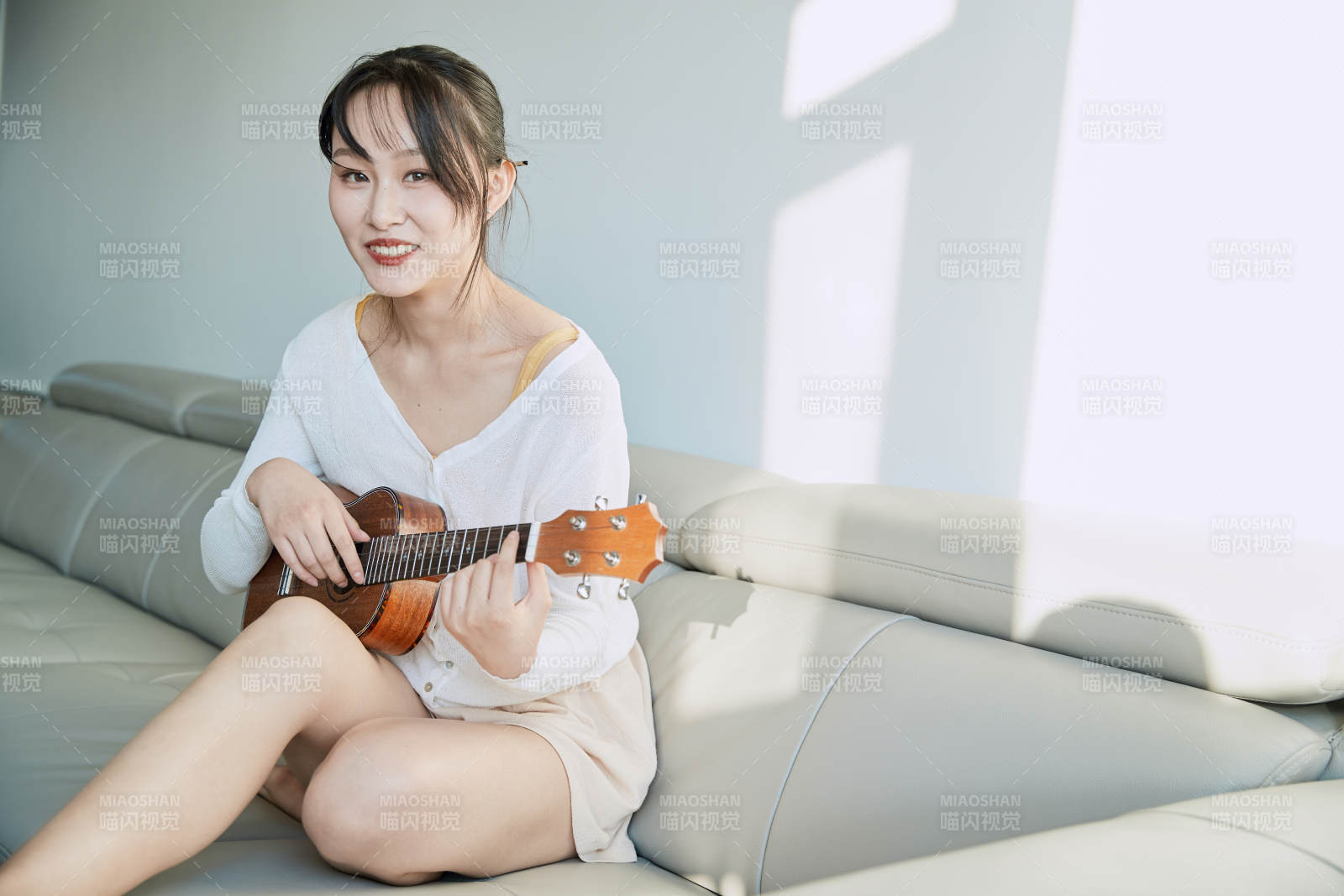 坐在沙发上弹奏尤克里里的少女图片