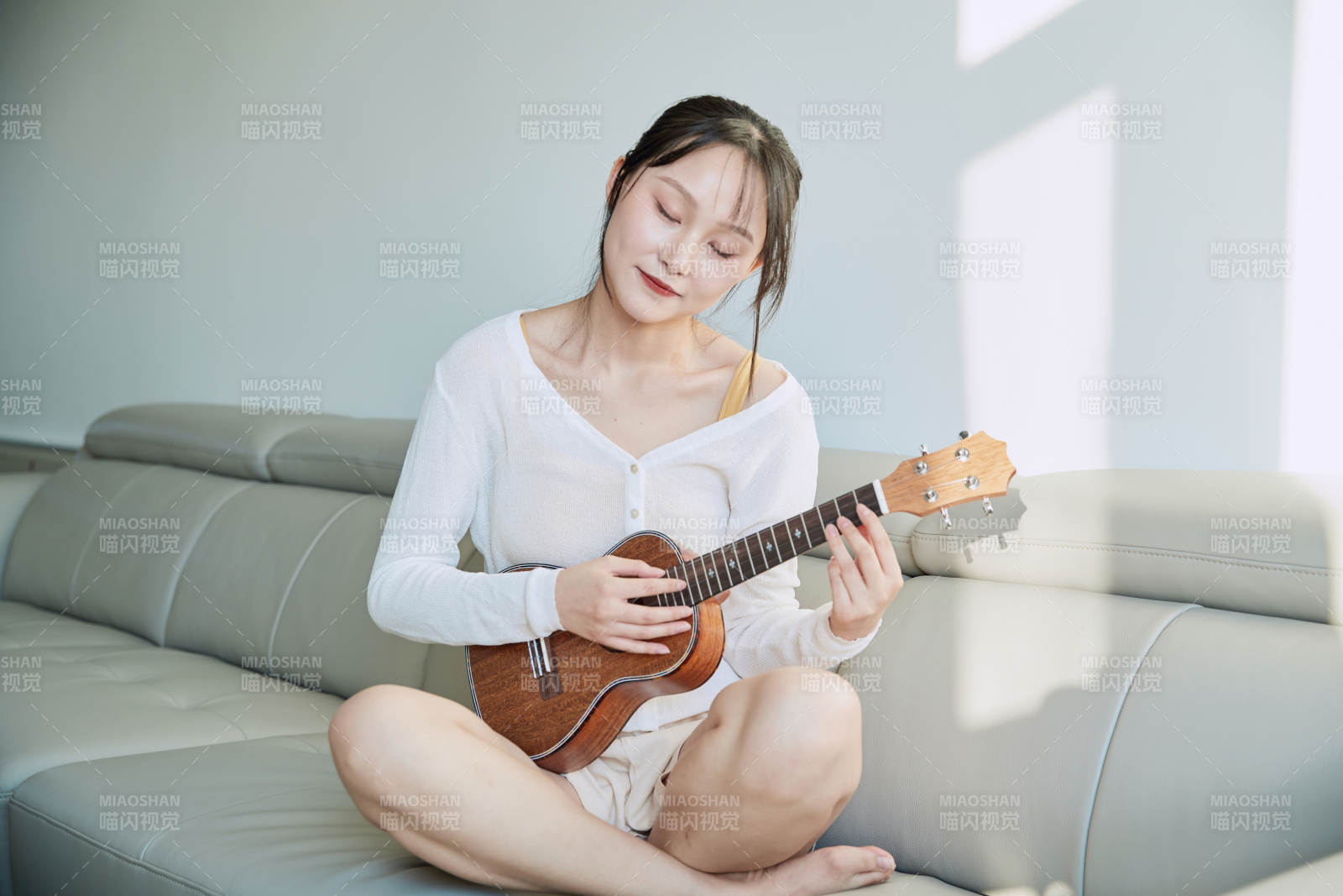 坐在沙发上弹奏尤克里里的少女图片