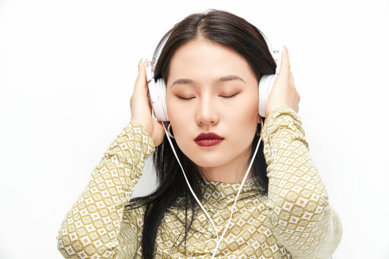 头戴耳机手持电话听音乐的少女图片