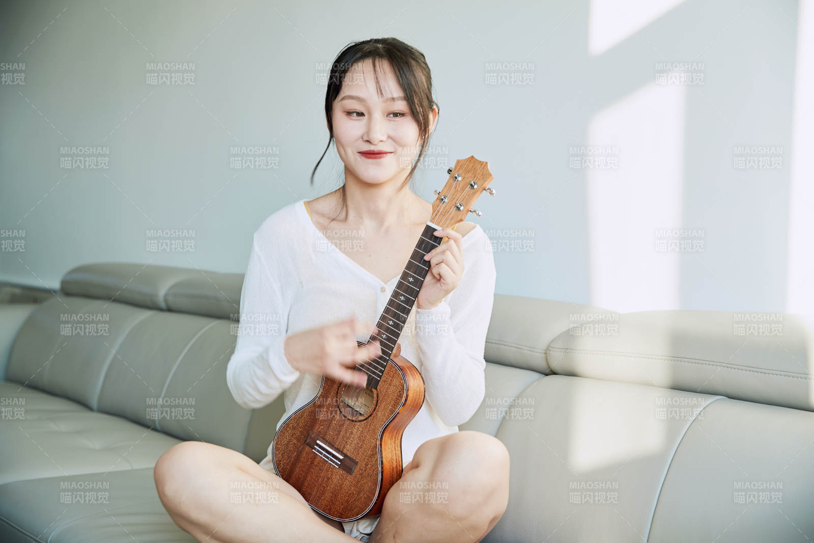 坐在沙发上弹奏尤克里里的少女图片