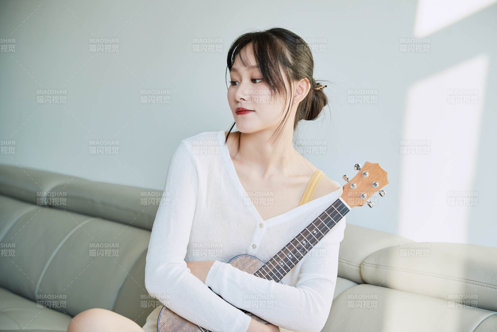 坐在沙发上弹奏尤克里里的少女图片