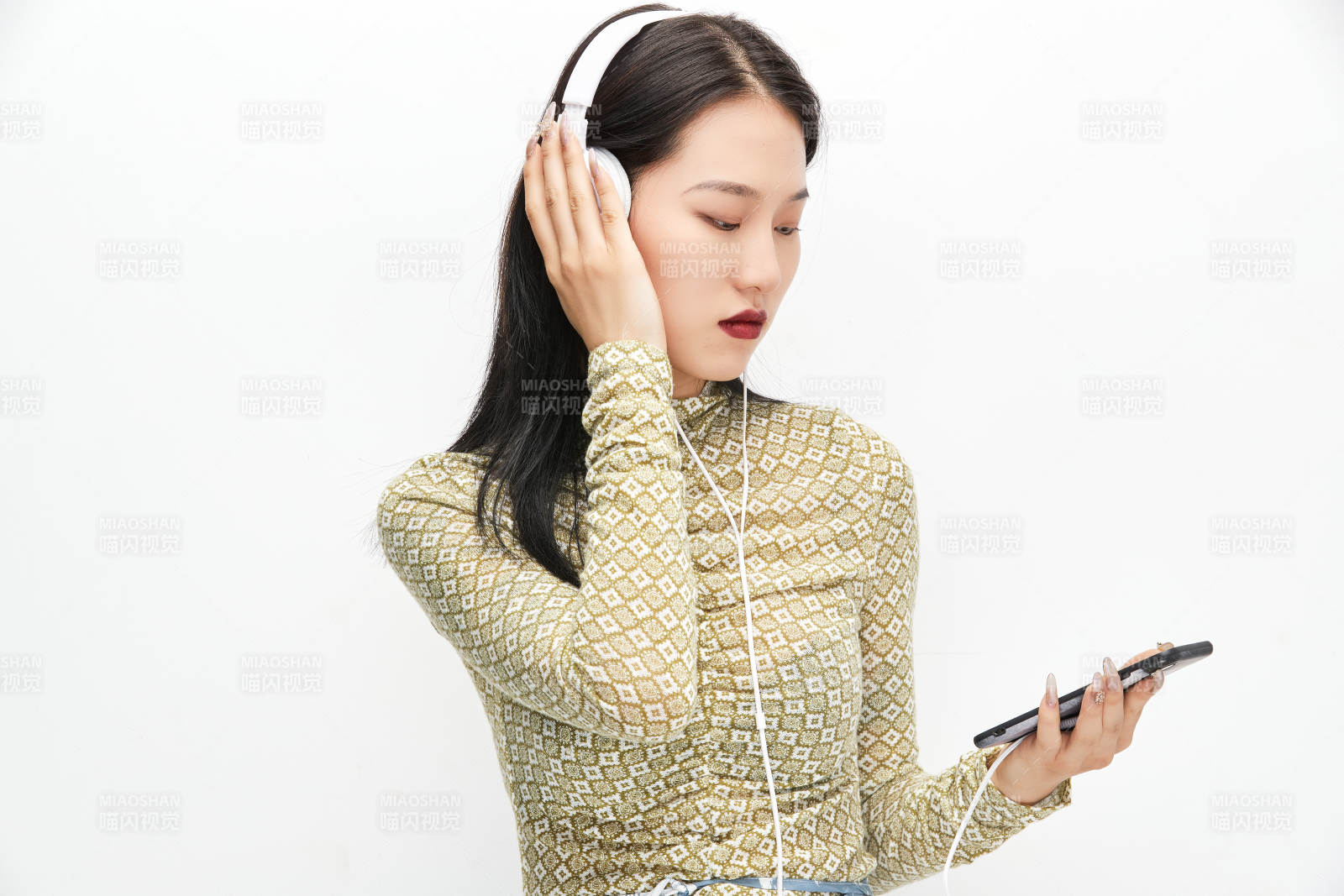 头戴耳机手持电话听音乐的少女图片