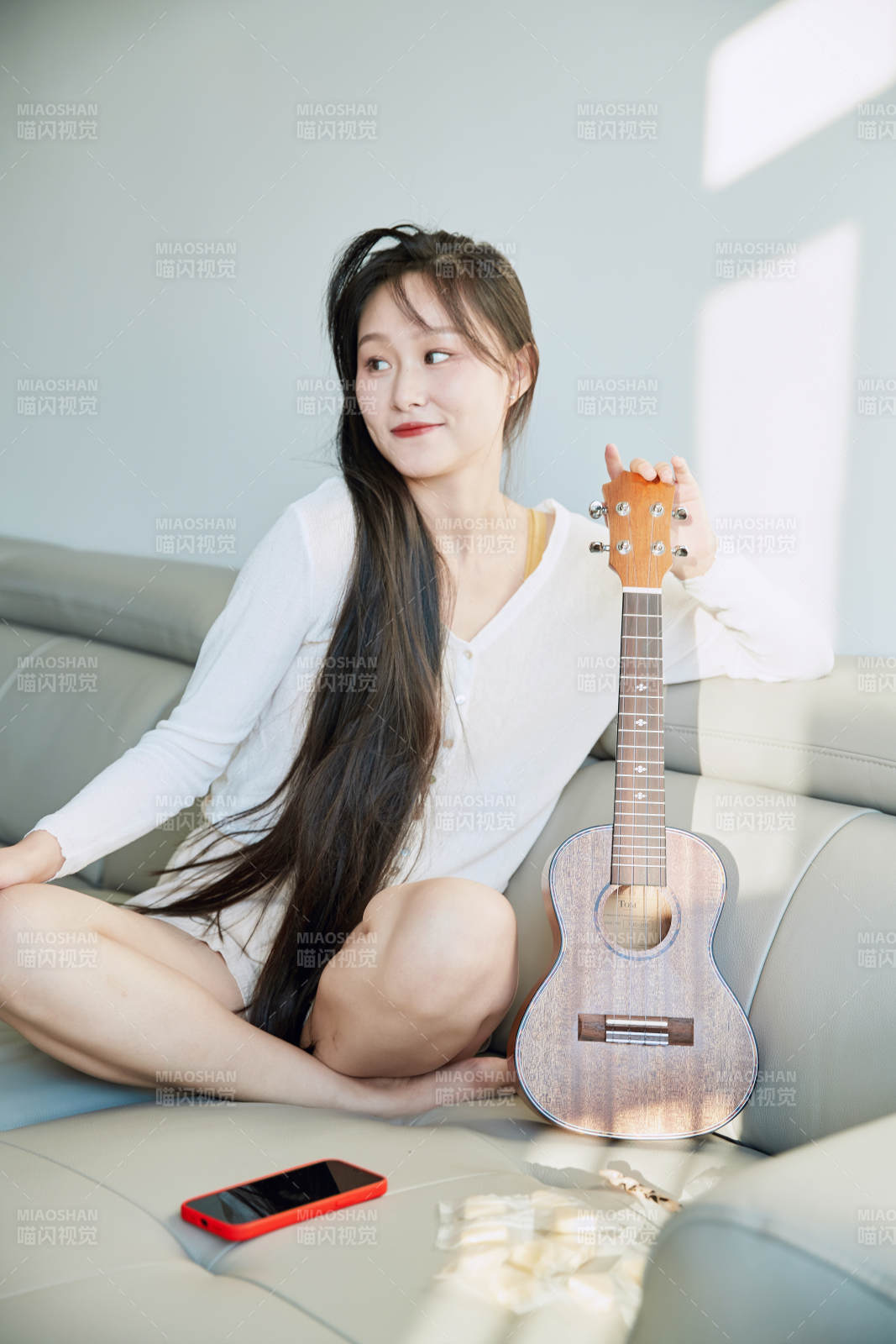 坐在沙发上弹奏尤克里里的少女图片