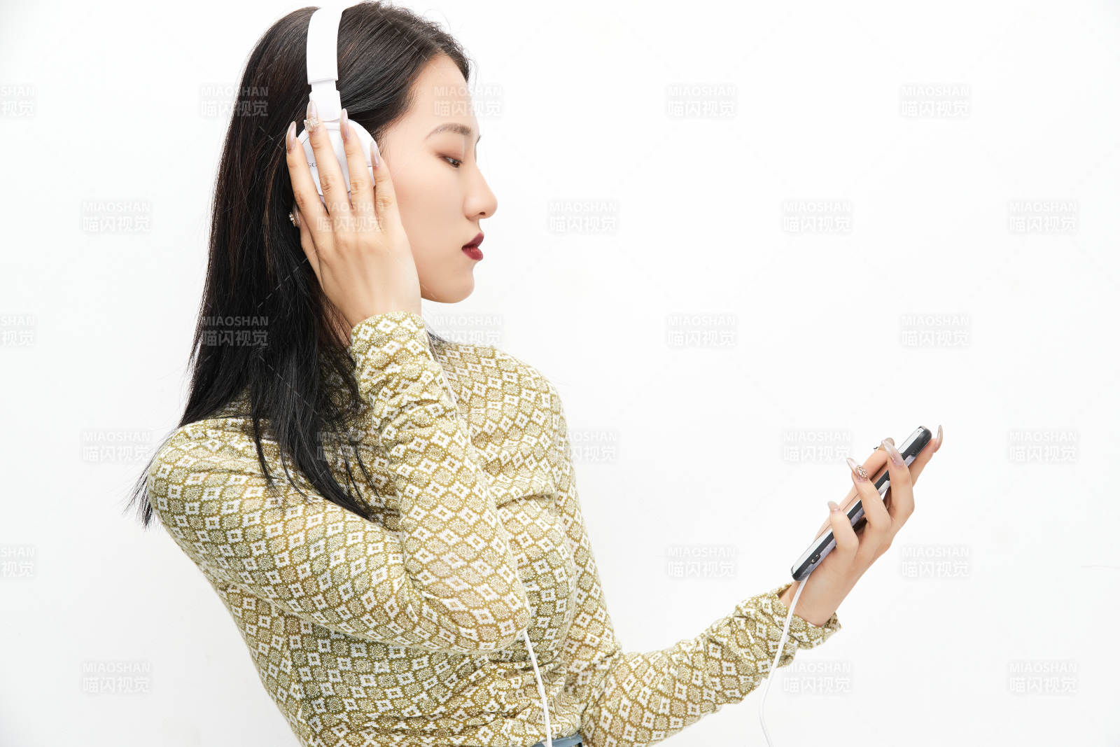 头戴耳机手持电话听音乐的少女图片