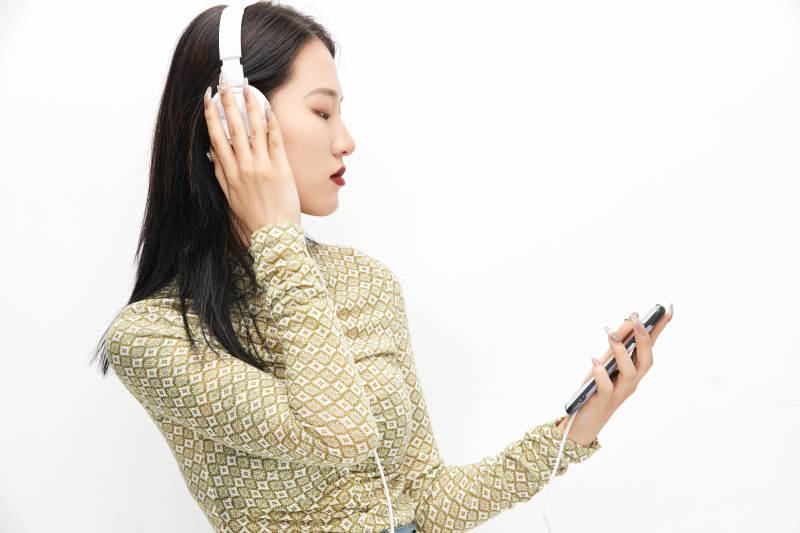 头戴耳机手持电话听音乐的少女图片