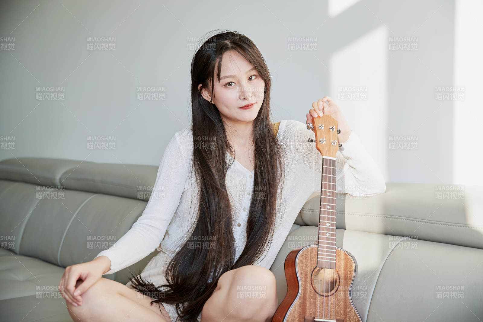 坐在沙发上弹奏尤克里里的少女图片
