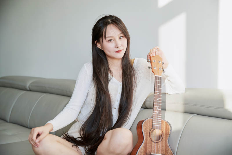 坐在沙发上弹奏尤克里里的少女图片