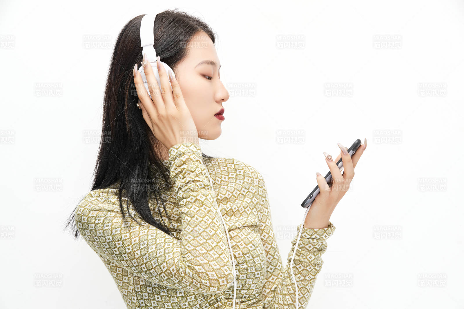 头戴耳机手持电话听音乐的少女图片