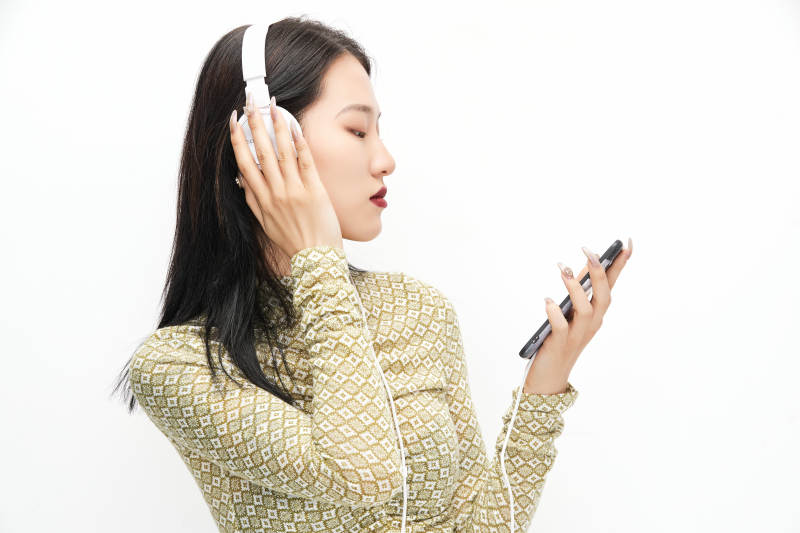 头戴耳机手持电话听音乐的少女图片