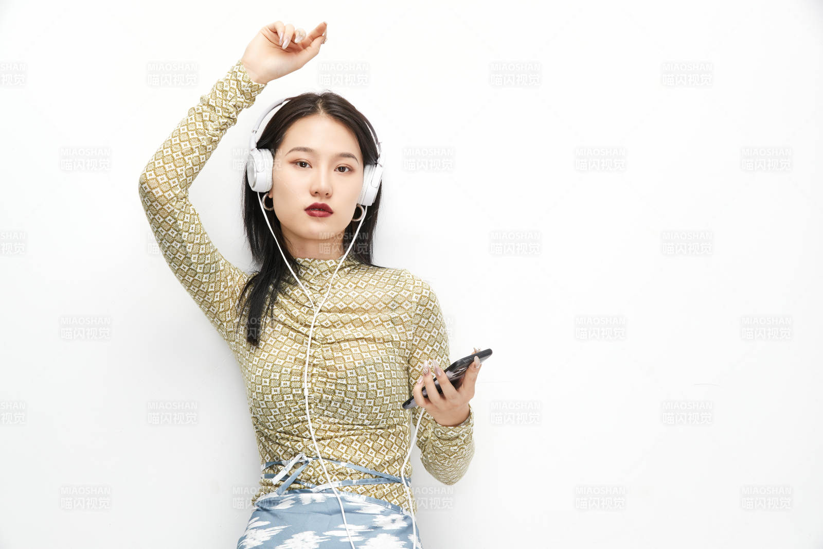 头戴耳机手持电话听音乐的少女图片