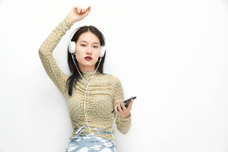 头戴耳机手持电话听音乐的少女图片