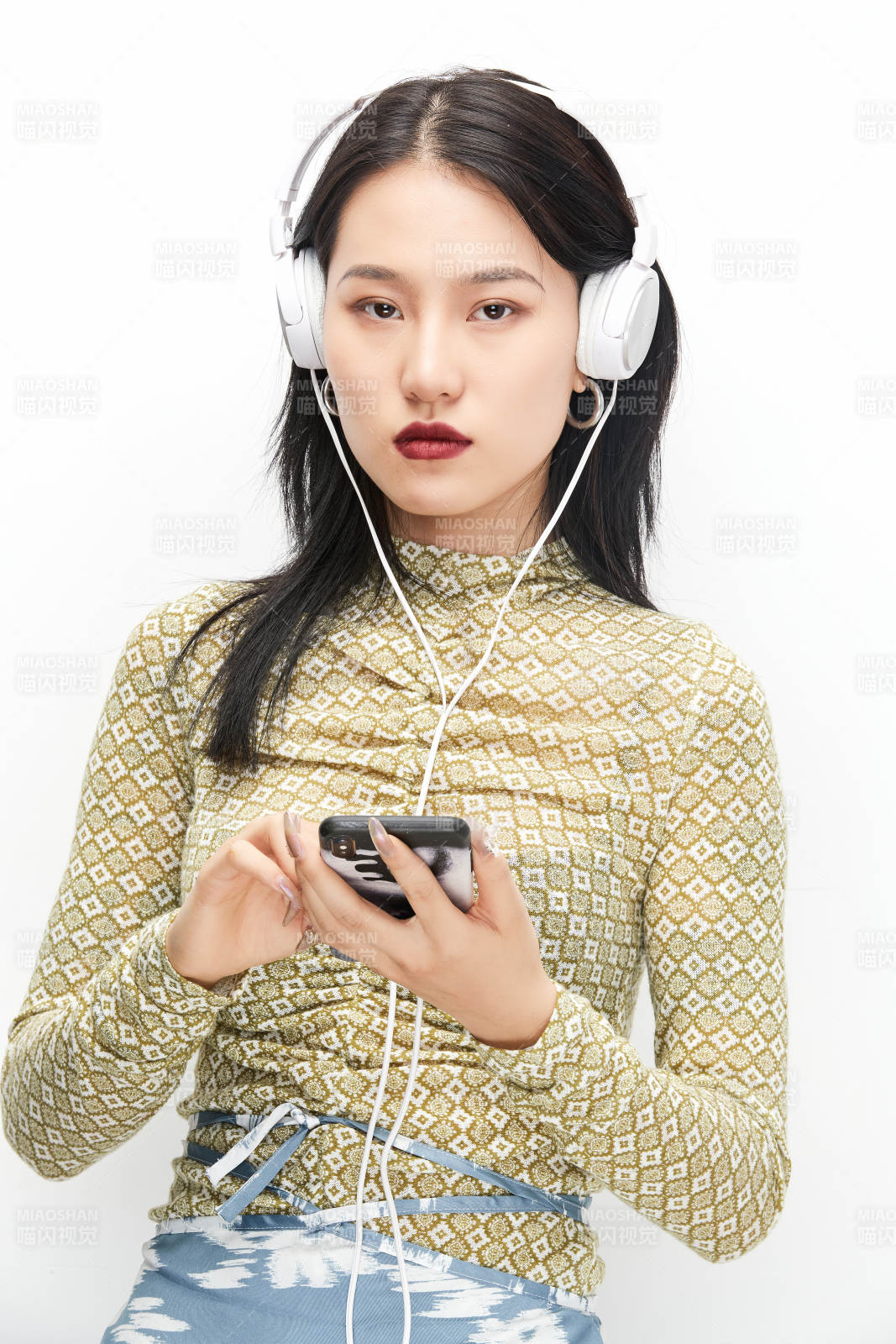 头戴耳机手持电话听音乐的少女图片