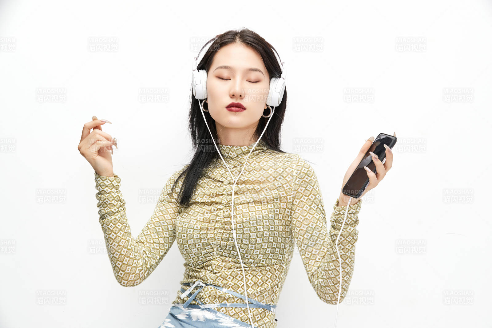 头戴耳机手持电话听音乐的少女图片