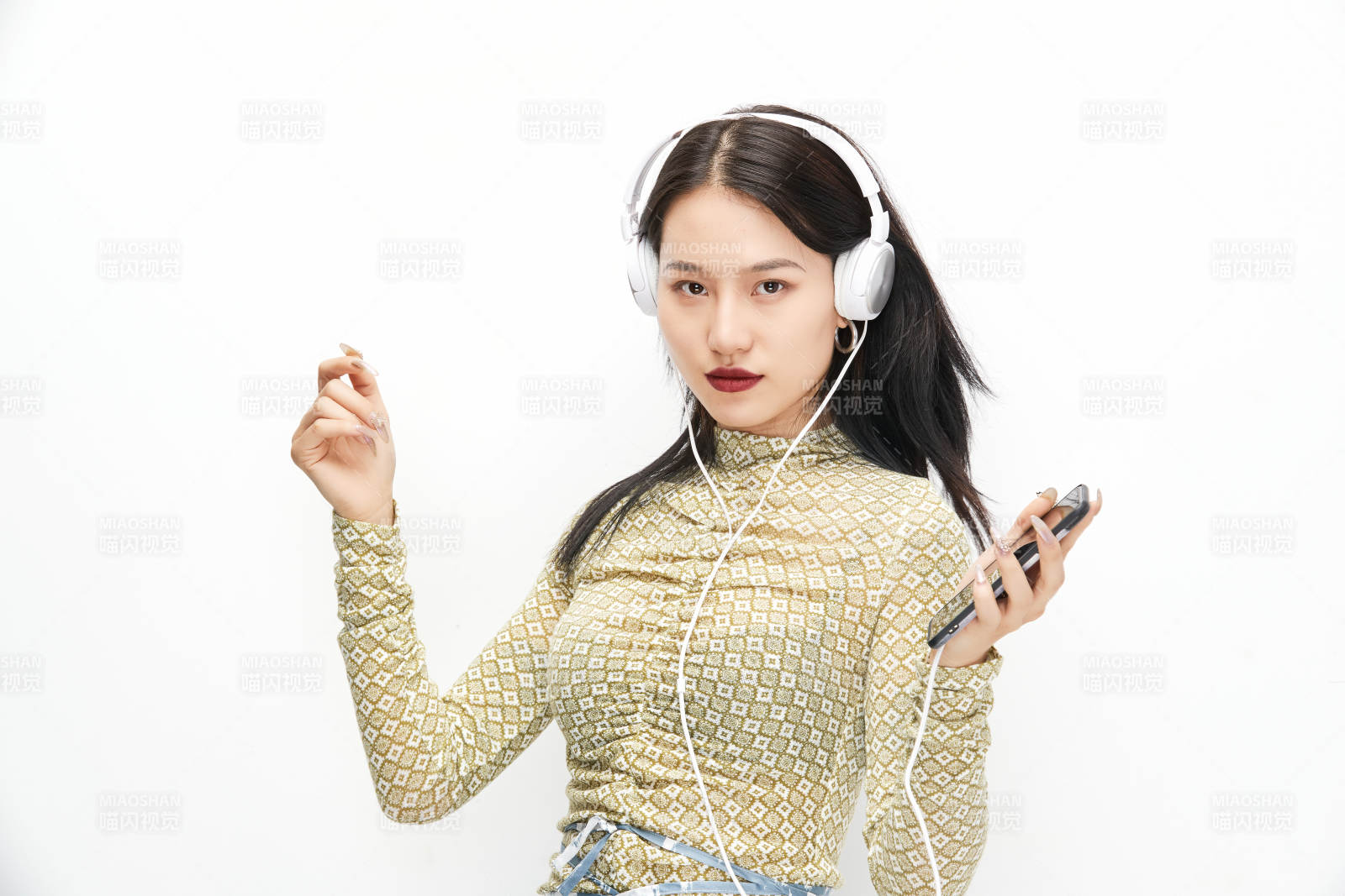 头戴耳机手持电话听音乐的少女图片