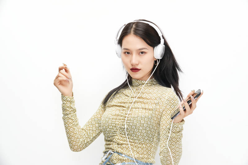头戴耳机手持电话听音乐的少女图片