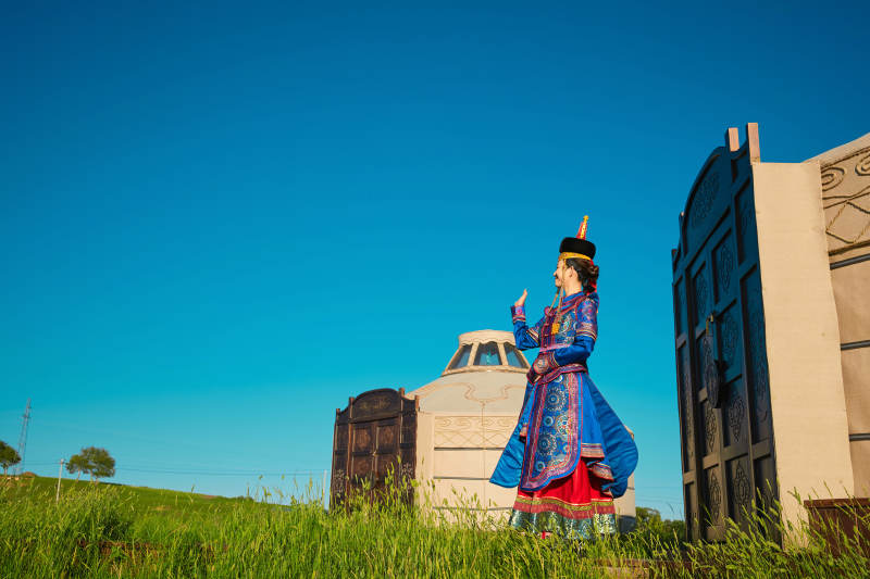 夕阳下草原蒙古大帐前穿蒙族服饰的美女图片