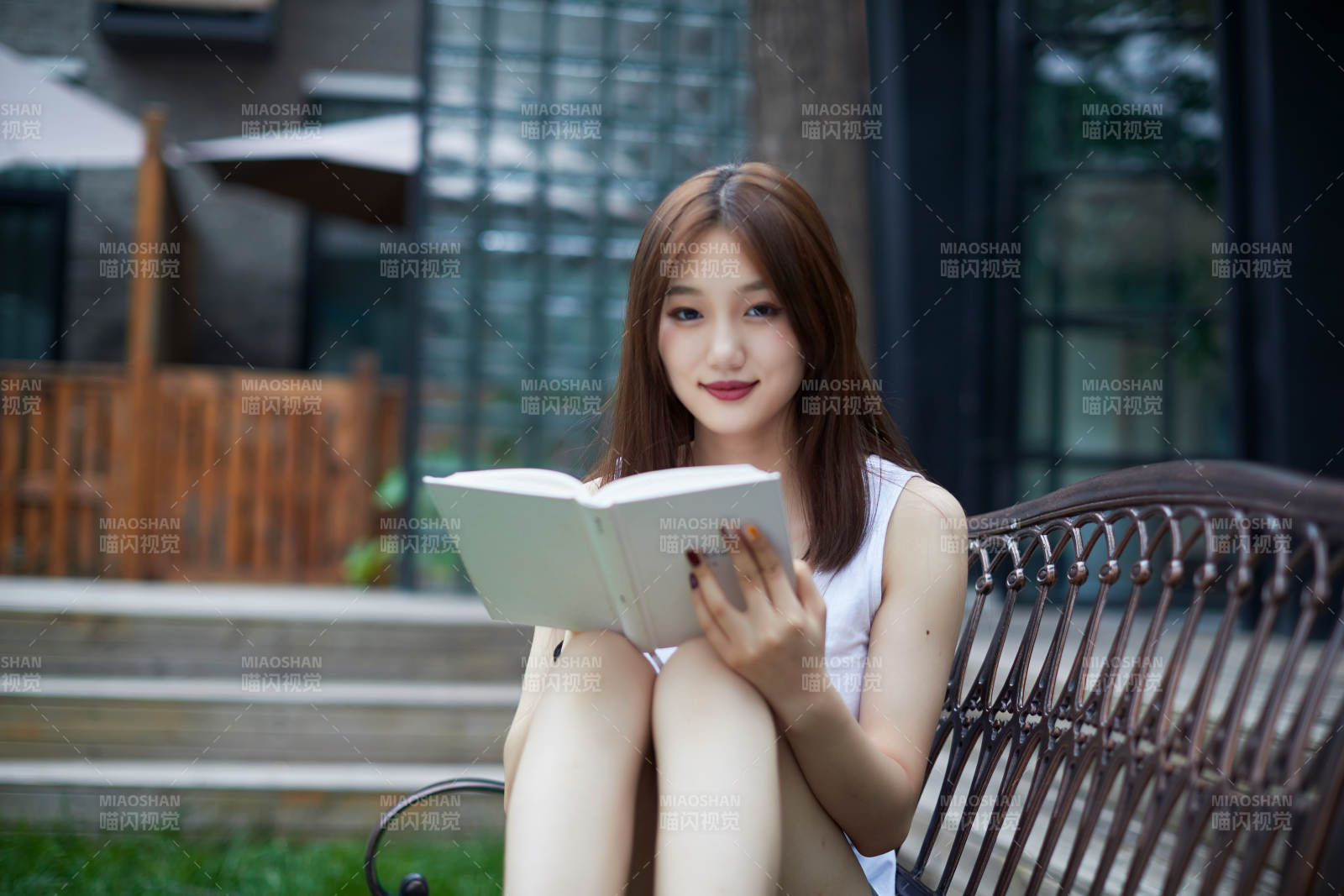 院子里坐在长椅上阅读书籍的亚洲长发少女图片