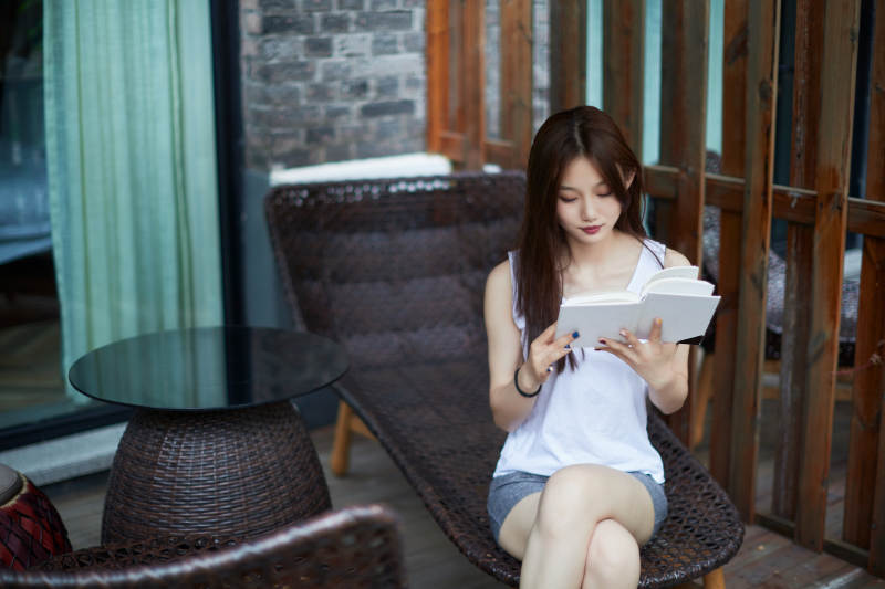 院子里坐在长椅上阅读书籍的亚洲长发少女图片