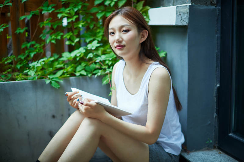 院子里坐在长椅上阅读书籍的亚洲长发少女图片