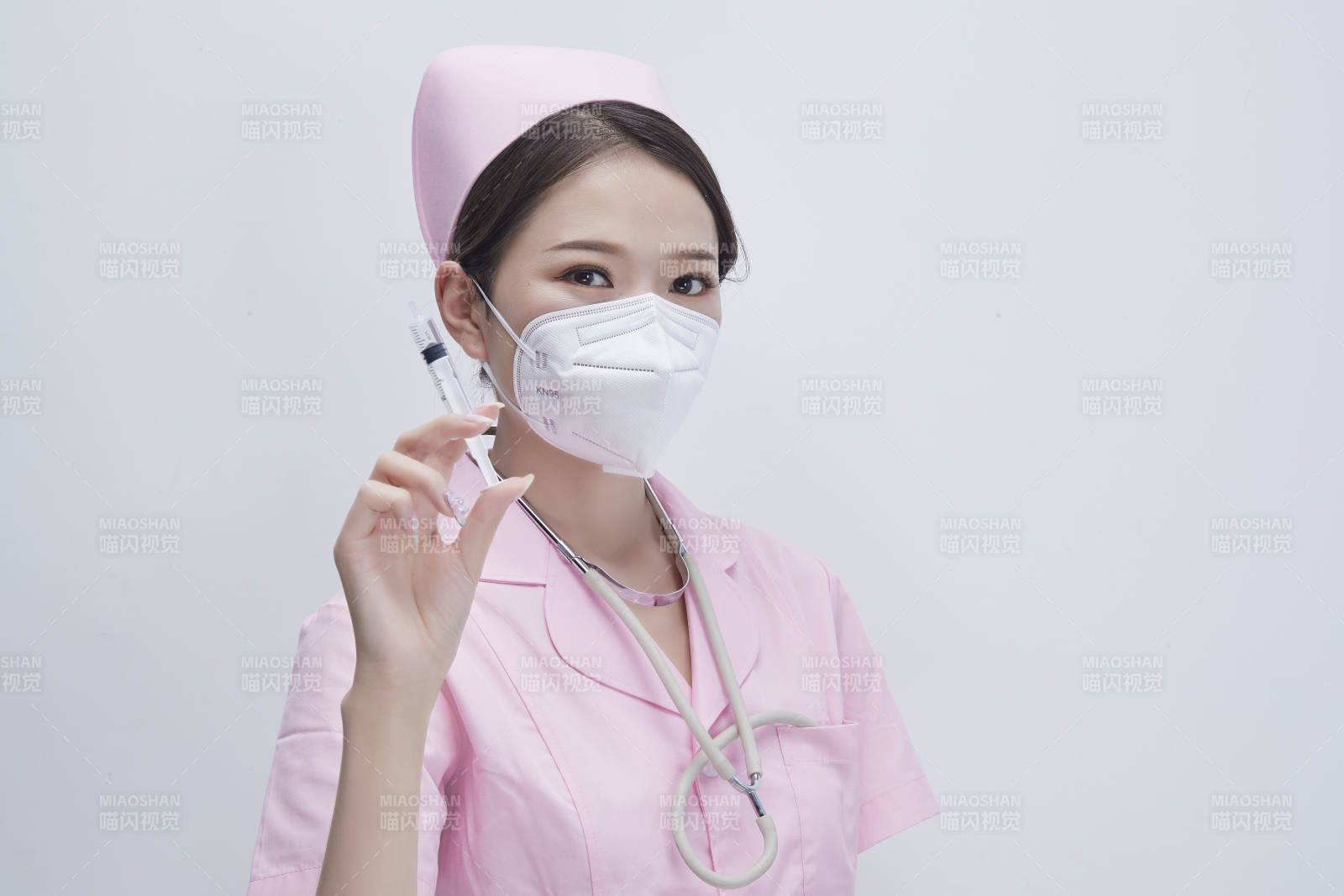 穿护士服戴听诊器口罩手执针筒的年轻女护士图片