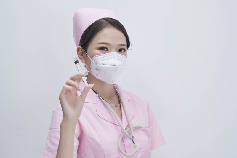 穿护士服戴听诊器口罩手执针筒的年轻女护士图片