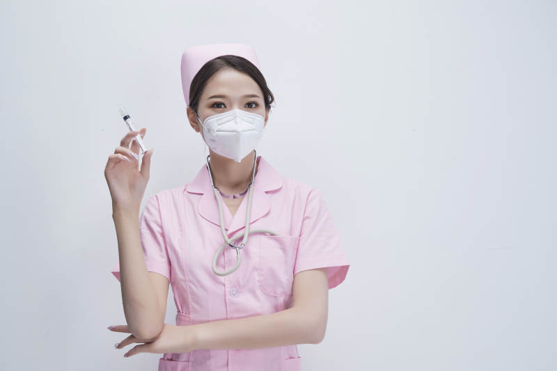 穿护士服戴听诊器口罩手执针筒的年轻女护士图片