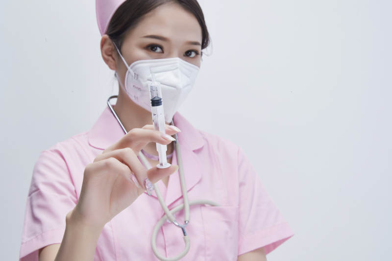 穿护士服戴听诊器口罩手执针筒的年轻女护士图片