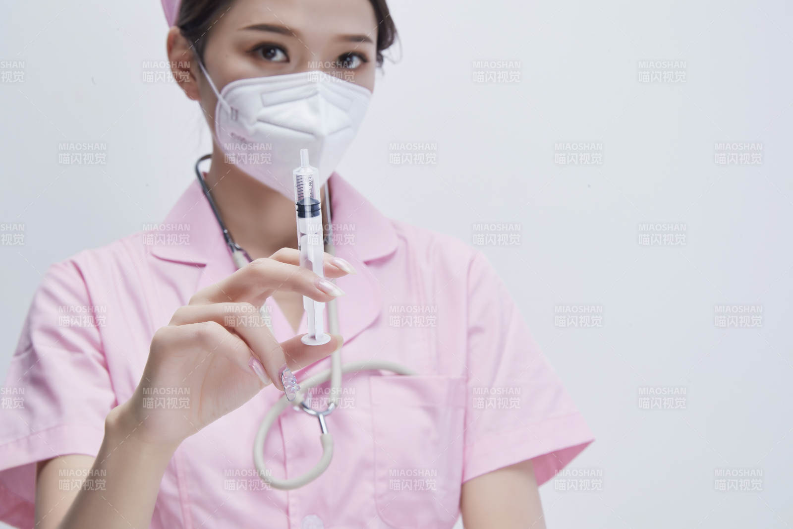 穿护士服戴听诊器口罩手执针筒的年轻女护士图片