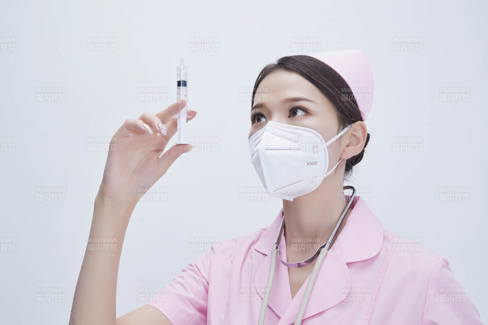 穿护士服戴听诊器口罩手执针筒的年轻女护士图片