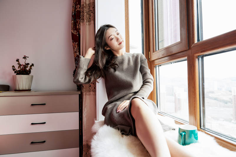 躺在舒适的飘窗上喝咖啡的少女图片