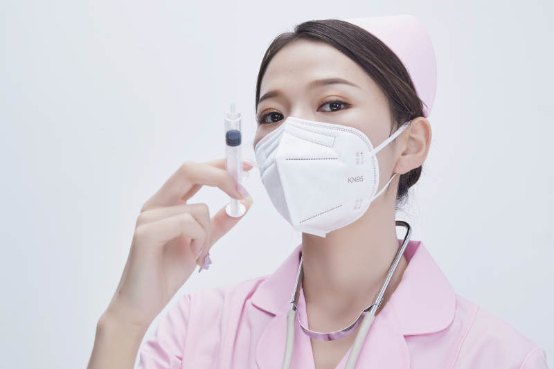 穿护士服戴听诊器口罩手执针筒的年轻女护士图片