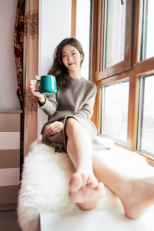 躺在舒适的飘窗上喝咖啡的少女图片