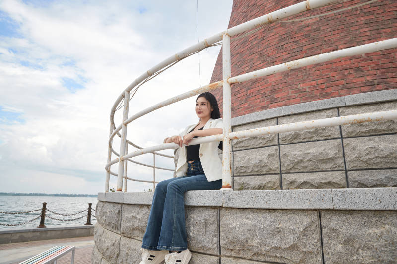 盛夏在景区湖边灯塔上拍照游玩的美女图片