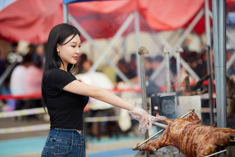 在户外烤全羊自助餐会品尝美食的美女图片