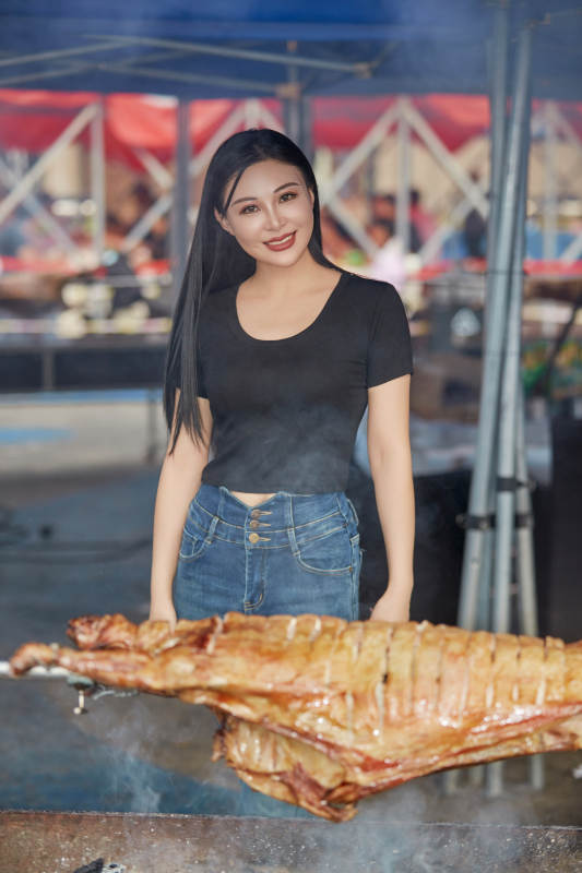 在户外烤全羊自助餐会品尝美食的美女图片