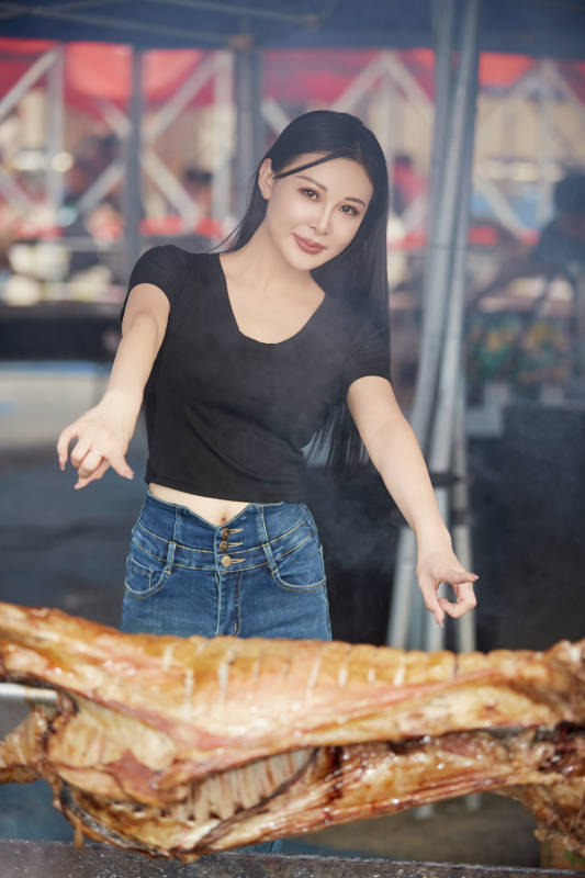 在户外烤全羊自助餐会品尝美食的美女图片