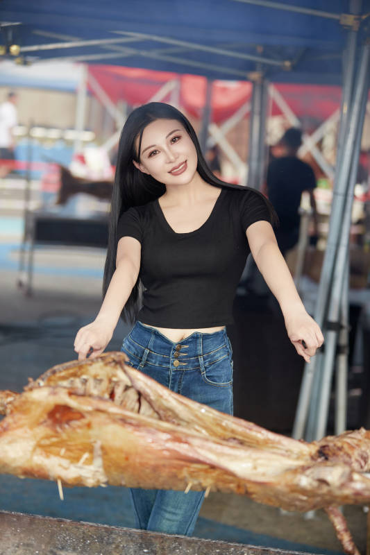 在户外烤全羊自助餐会品尝美食的美女图片